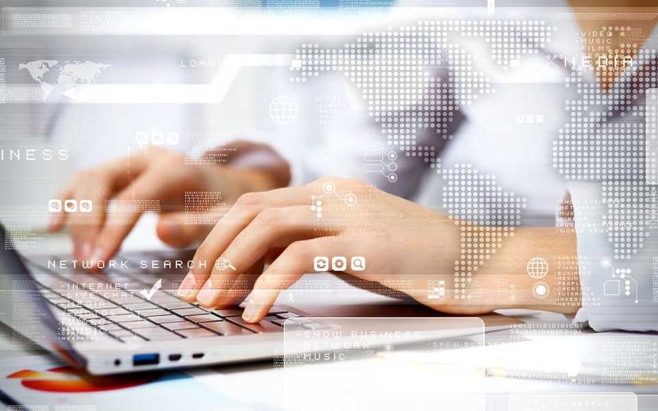 A woman writing on a laptop, shaded by a world map. Concept of translation technology and translation devices.