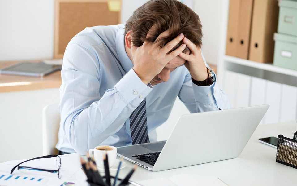 An employee wearing a blue shirt and tie, his head bowed. Concept of mistakes in certified legal translations.