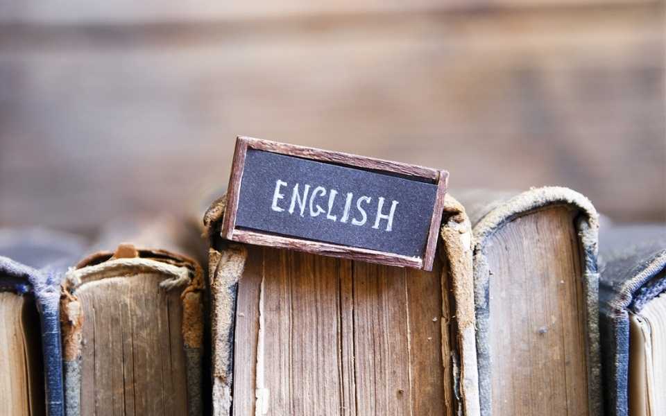 The word English on a cardboard sign attached to a book. Concept of the English language.