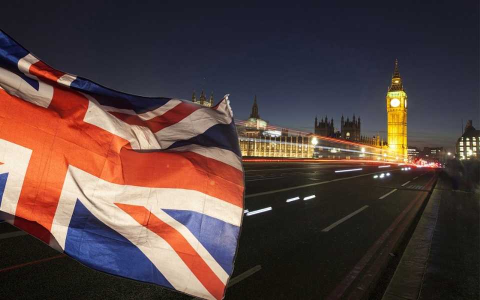 The flag of The United Kingdom and the Big Ben at night flutters in London, Britain. Concept of language services and translation companies.