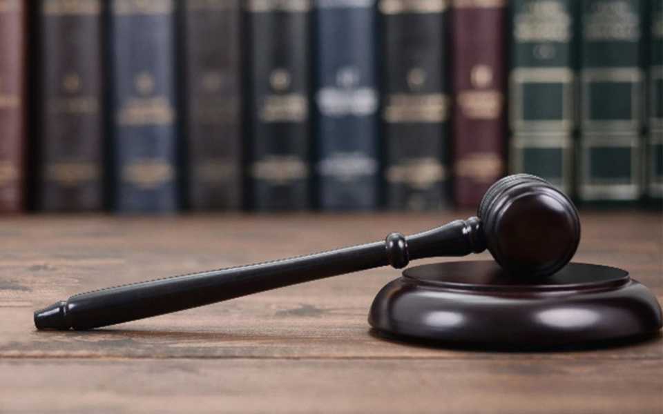 A brown judge's gavel on a desk in a library with books in the background. Concept of certified legal document translation.