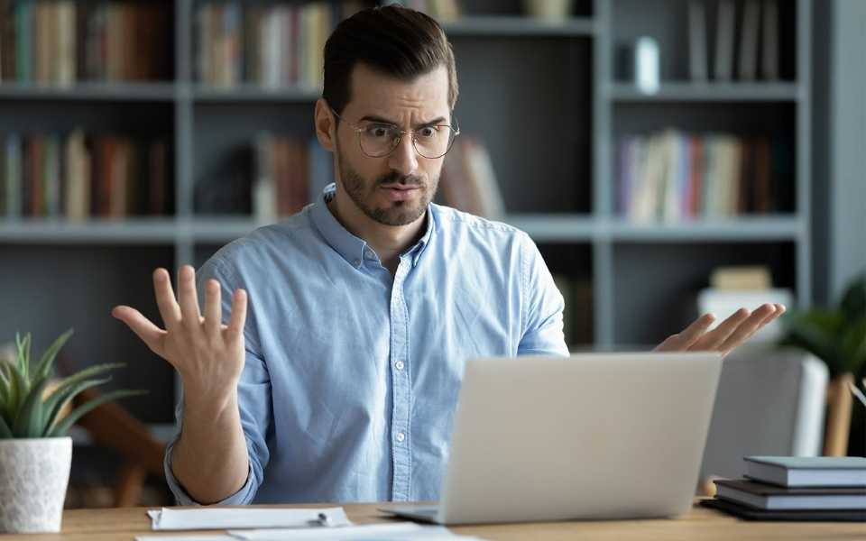 An employee raises his hands and looks nervously at laptop. Concept of terrible translation mistakes.