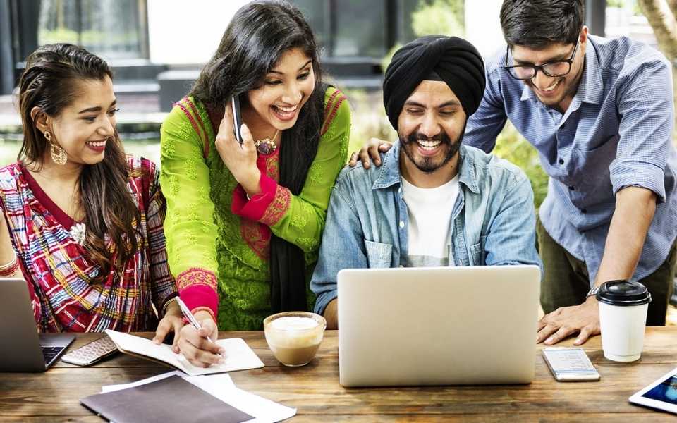 Two Indian women and two Indian men looking at their laptop. Concept of English to Hindi translation and Hindi translators.