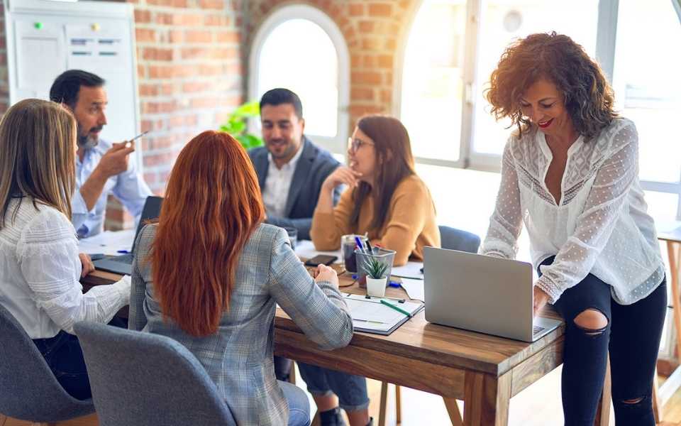 An employee sits at a conference table while her co-workers discuss work. Concept of business translation services.