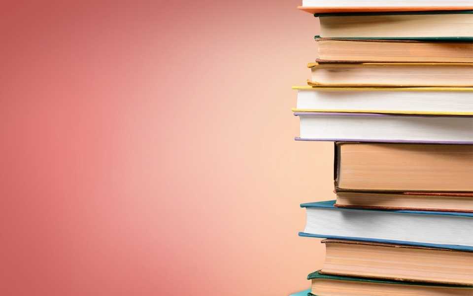 A group of coloured books and a library of books behind it. Concept of book translations.