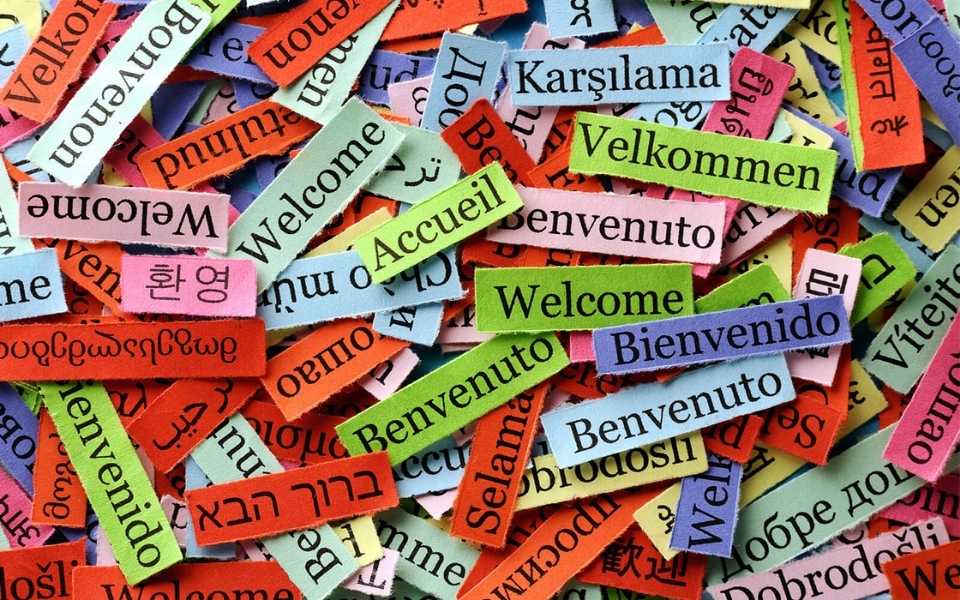 The word “welcome” written in different languages on small coloured scraps.