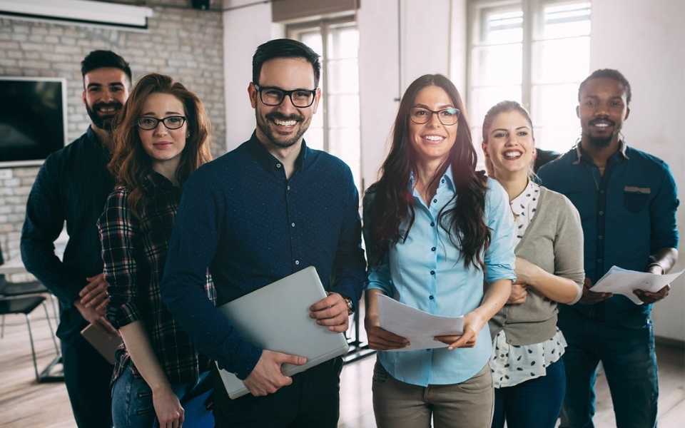 Employees standing next to each other and smiling to take a picture. Concept of translation services UK.