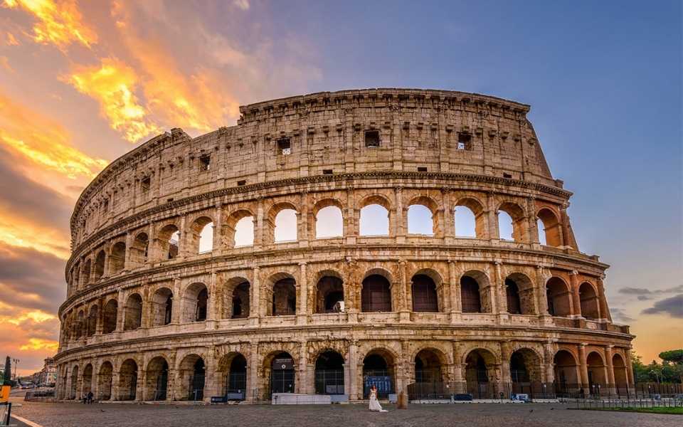 Sunrise behind the Colosseum in Rome, showing the beauty of ancient architecture. Concept of Italian translations.
