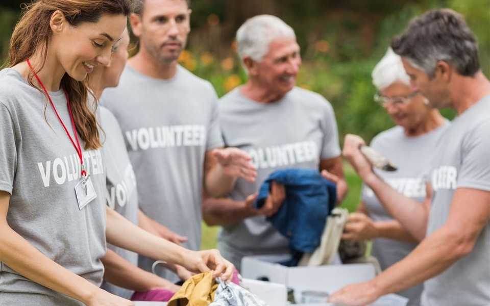 A group of volunteers working and wearing T-shirts with the word "Volunteers". Concept of charity translations.
