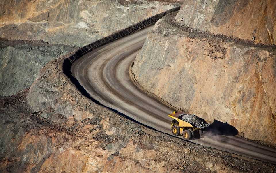Truck carrying black rocks driving on a mountain road. Concept of professional oil and gas translation services.