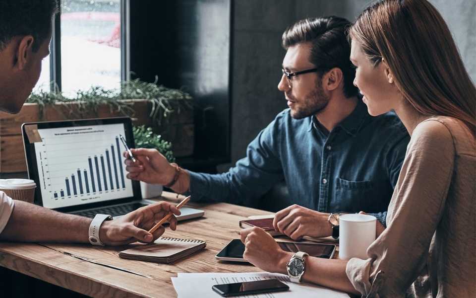 Three business professionals discuss and analyse a company's data. Concept of language translator services.