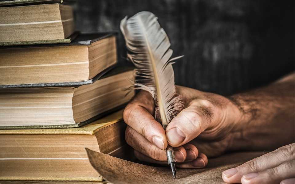 A man writes on old paper with a quill next to books. Concept of English language translators.
