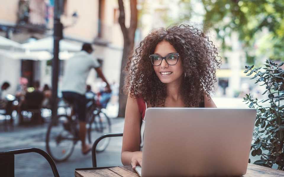 Female Caucasian freelancer wearing glasses and sitting in cafe. Concept of freelance translation jobs for translators.
