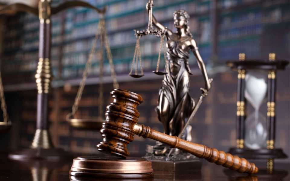 A judge's gavel on a desk in a library, next to a scale of justice. Concept of legal translations.