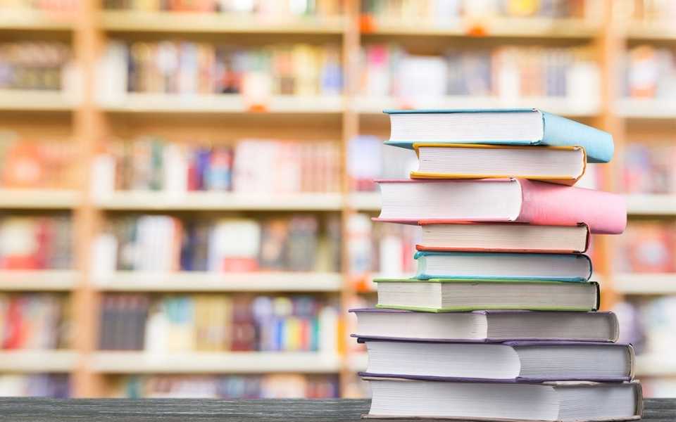 A group of coloured books and a library of books behind it. Concept of books translation.