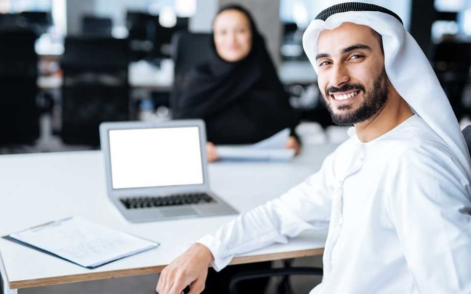 An Arab man with a laptop and a woman in hijab. Concept of translating English to Arabic.