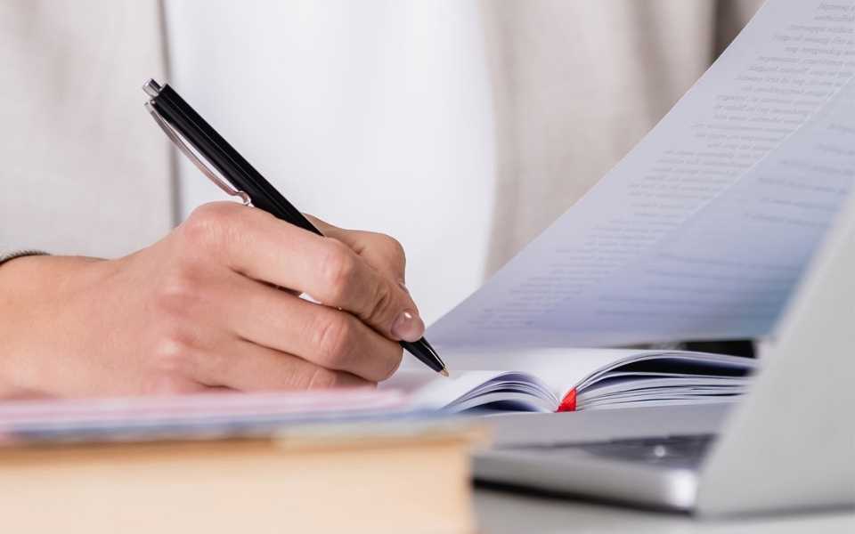 An employee reviews and checks information and takes notes with a computer. Concept of literal translation.