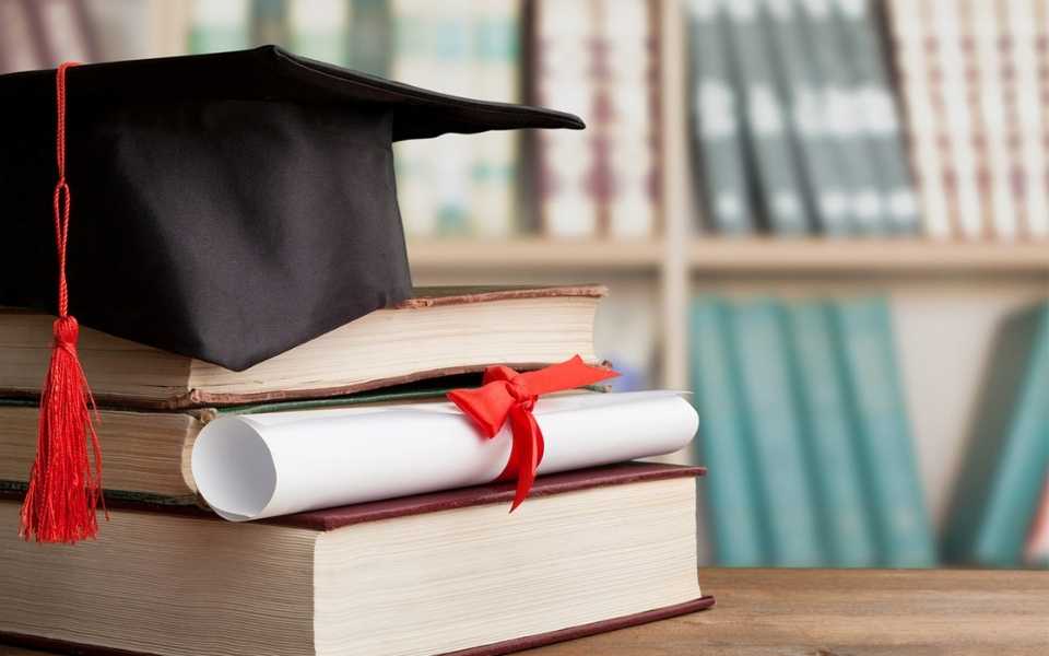 Books on a library table with a graduation cap certificate on top. Concept of education translation.