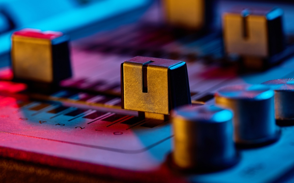 Close-up of a vintage audio mixer console with neon lights. Audiovisual translation of films and TV shows. 