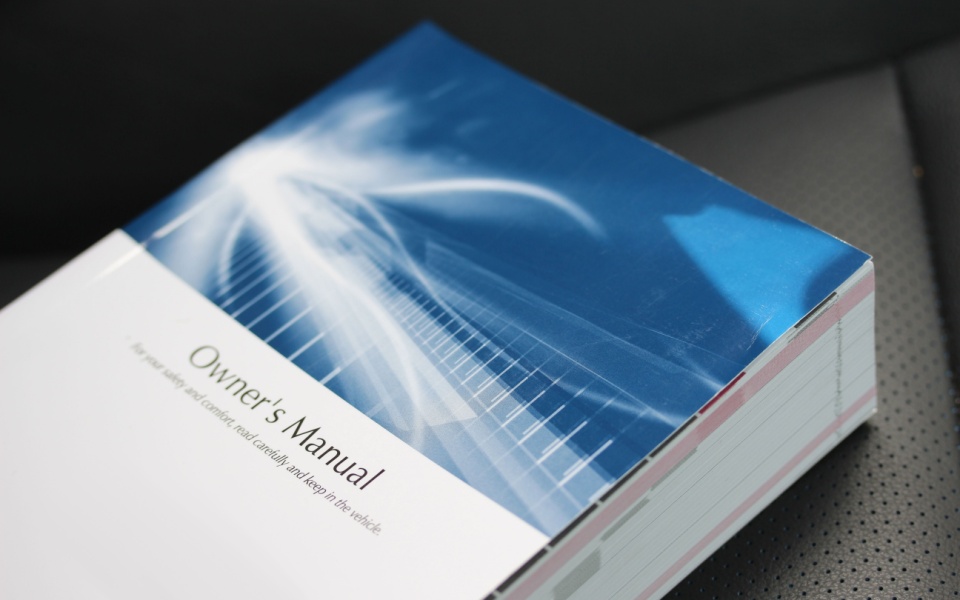 Technical user manual for translation lying on a black leather seat in a modern office. 