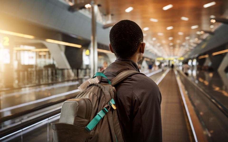 An African youth in airport with backpack and luggage for travel, immigration and migration. 