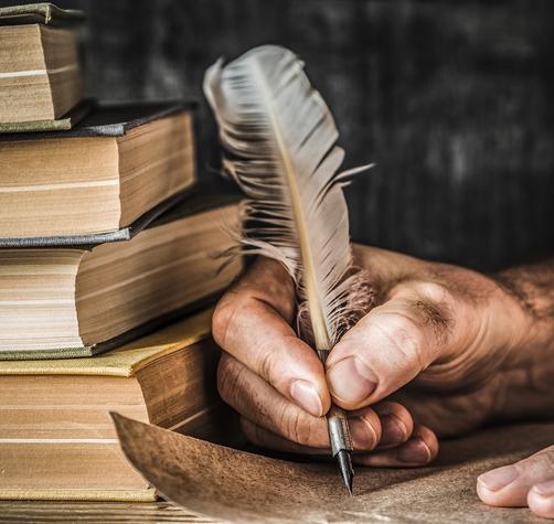 Man using an old quill pen to write an old letter with books aside. Concept of history of languages.