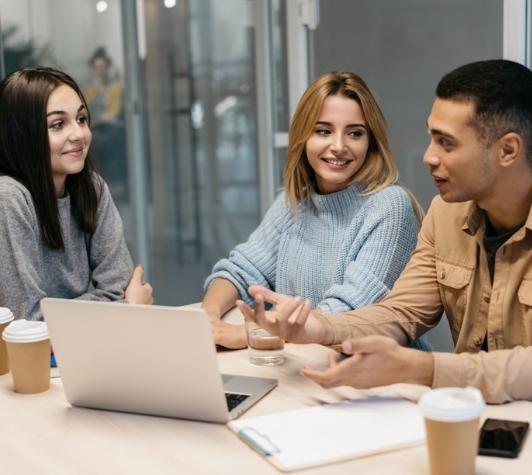 Two women and one man working on a table.