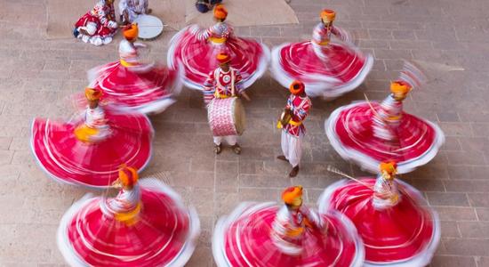8 men in red Indian costumes dancing in a circle. Concept of professional Hindi translators.