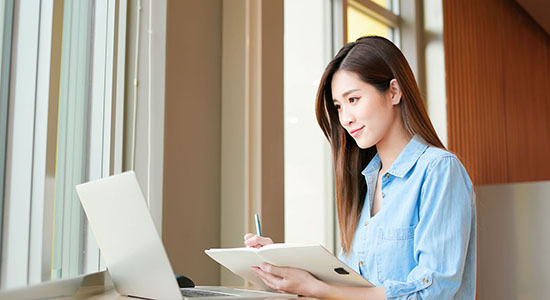 Chinese woman working on laptop in office.