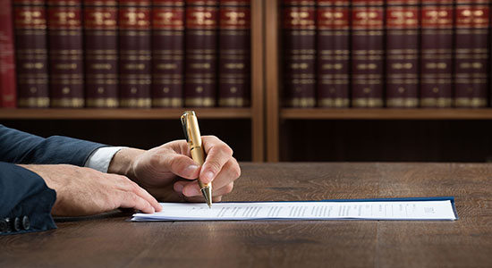 Male lawyer writing on documents in courtroom. Concept of legal Afrikaans translation.