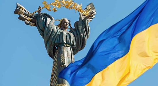 The bronze Ukrainian independence monument and a Ukrainian flag. Concept of English to Ukrainian translation services.