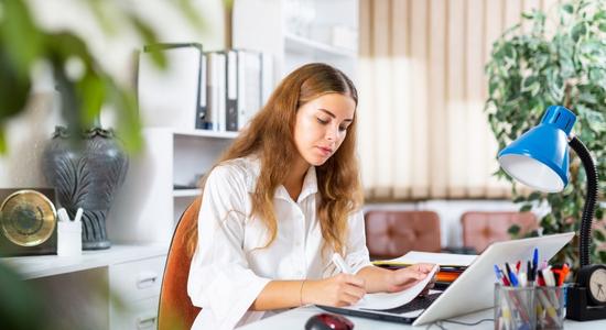 Greek woman working on laptop in office. Concept of Greek translators.