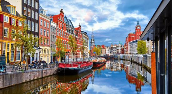 An Amsterdam canal, surrounded by colorful buildings in the traditional Dutch style. Concept of English to Dutch translation.