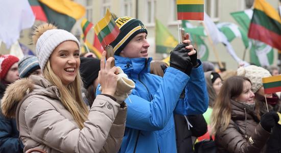 People holding the flag of Lithuania in the street.