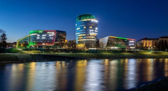 The skyline of Vilnius at night, with several large glass buildings. 
