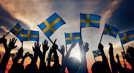 Backlit silhouettes of people waving Swedish flags. Concept of professional Swedish translators.