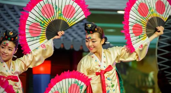 A smiling woman dancing in traditional South Korean costume. Concept of professional Korean translators.