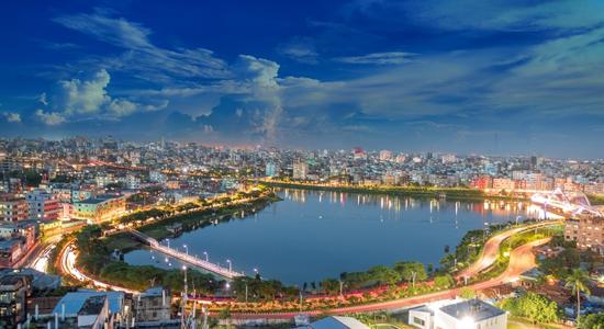 A nighttime overview of Dhaka with a waterfront and background cityscape.