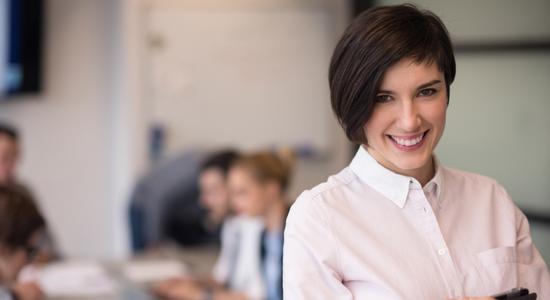 Professional woman standing in the office with her colleagues in the background. Concept of professional Armenian translators.