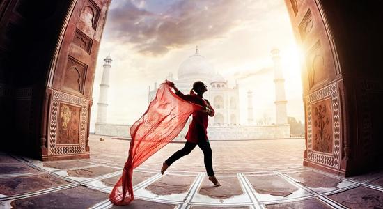 A woman dancing, holding a red cloth, the Taj Mahal behind her. Concept of English to Hindi translation.