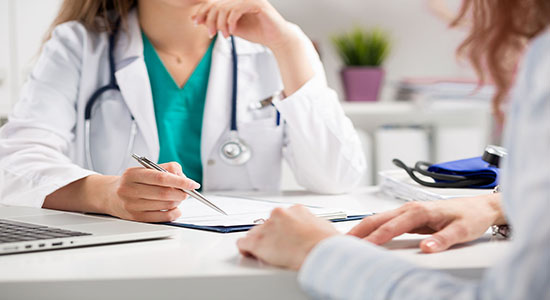 A close-up of two female doctors in scrubs and white coats discussing. 