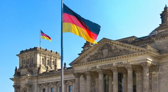Flag of Germany appearing on the parliament building. Concept of English to German translation services.