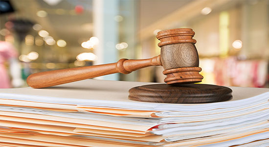 A wooden gavel on table with papers scattered on the table. Concept of legal Gujarati translation.