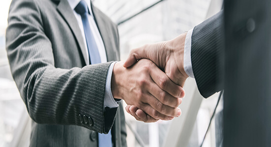 Two businessmen wearing suits shaking hands. 