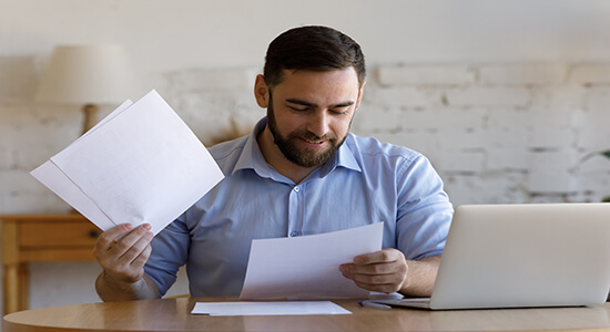 A professional businessman working with paperwork and laptop on desk. Concept of legal Slovenian translation.