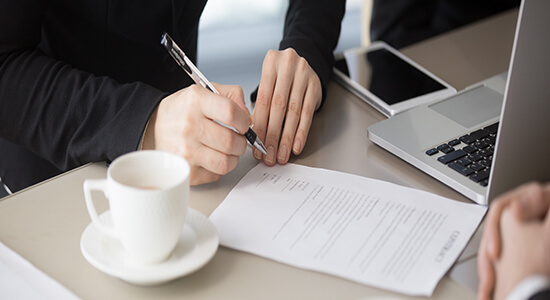 A businessman holding a pen and signing an agreement. Concept of certified legal Swahili translation.