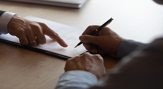 A lawyer pointing at a document and another man signing. Concept of legal Slovak translation.