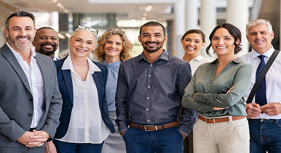 Business people smiling at camera while standing in a modern office.