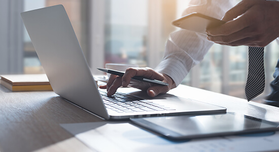 Businessman using mobile and laptop.