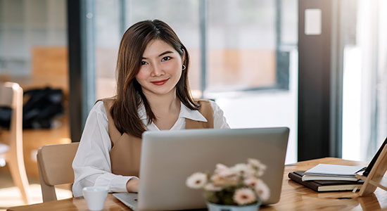 Professional Asian woman working on laptop in office. 